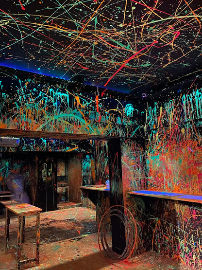 A room covered in neon paint splatters, with tables and counters also painted.