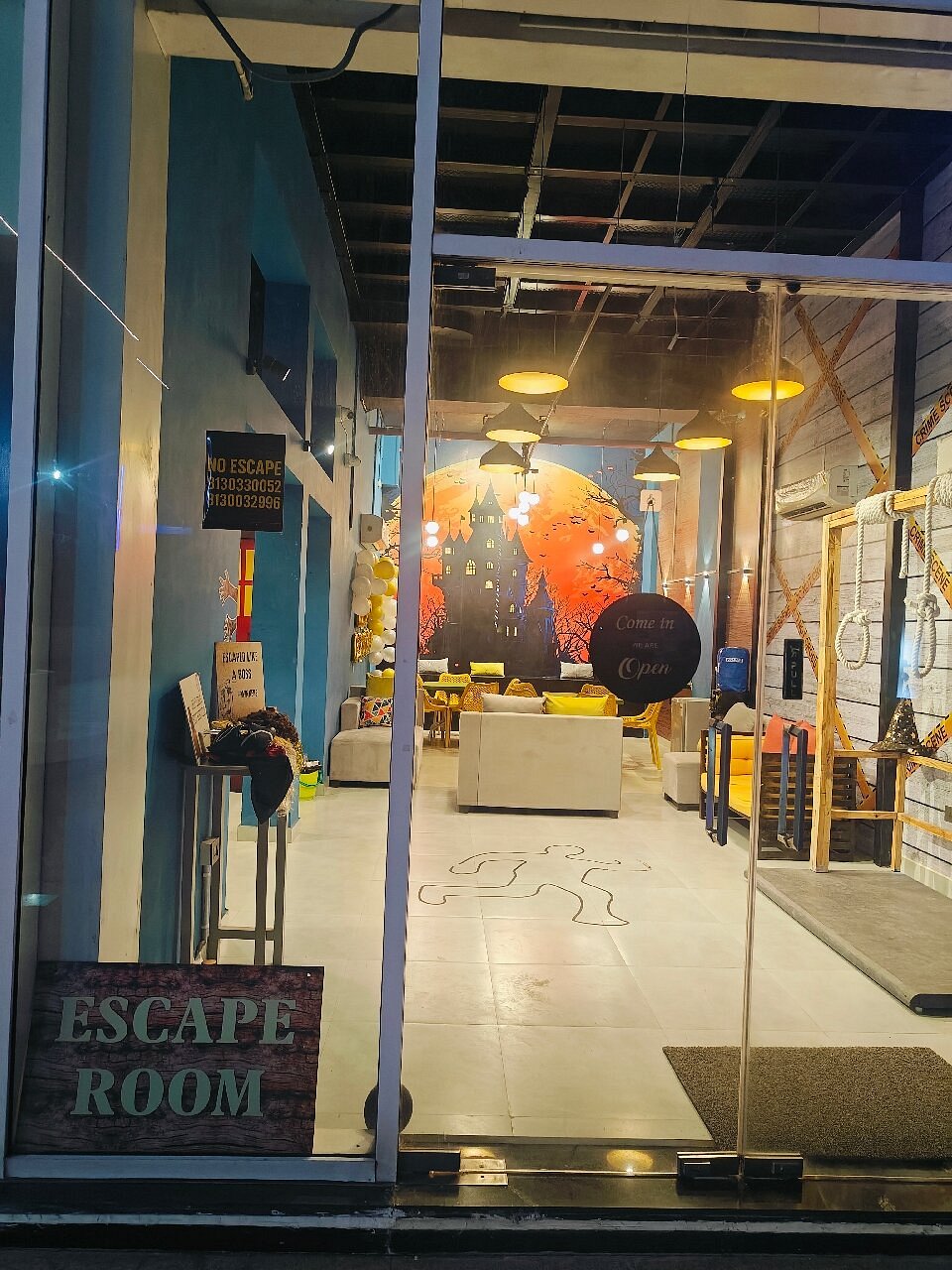 An escape room entrance with a spooky mural and a "Come in, we're open" sign.