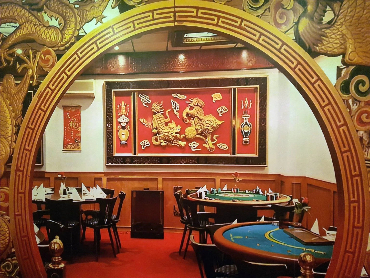 An ornate Chinese-themed restaurant interior with dragon decor, featuring dining tables and gaming tables.
