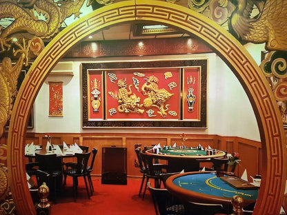 An ornate Chinese-themed restaurant interior with dragon decor, featuring dining tables and gaming tables.