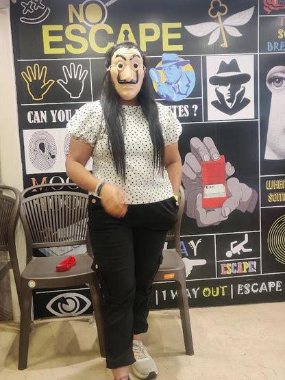 A person in a Salvador Dalí mask stands in front of a "No Escape" themed wall. The wall features graphics related to puzzles and escape rooms.
