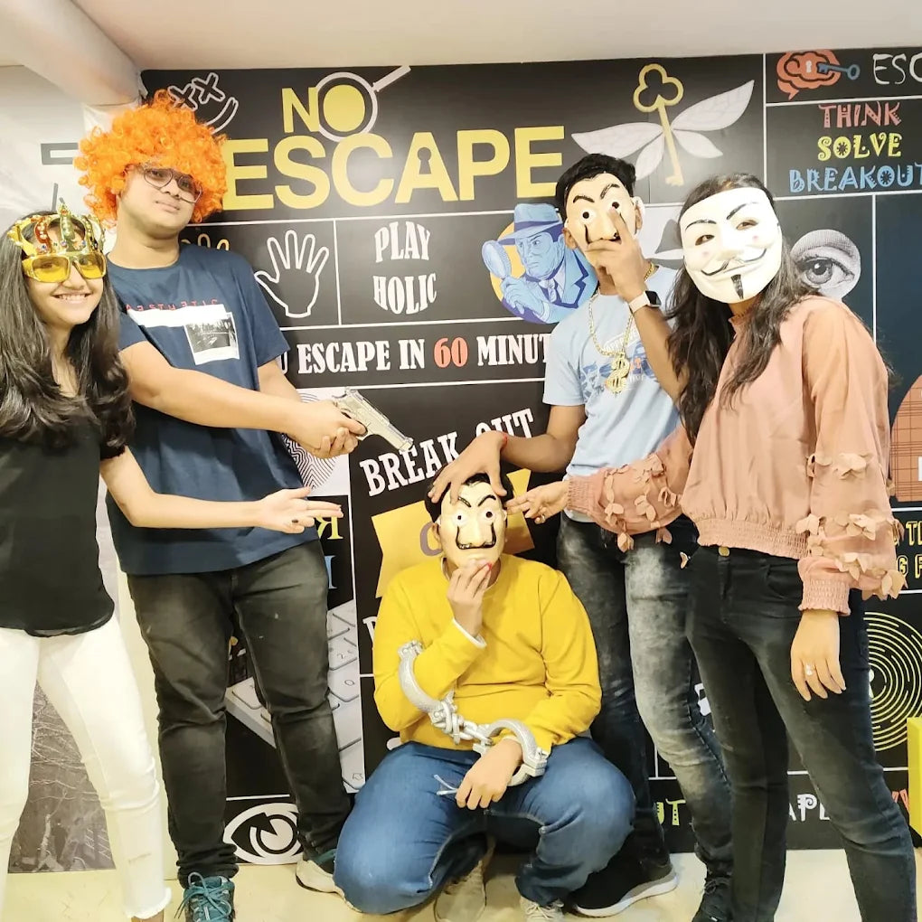 A group of young adults poses for a photo in front of a "No Escape" themed wall, some wearing masks and one holding a toy gun.
