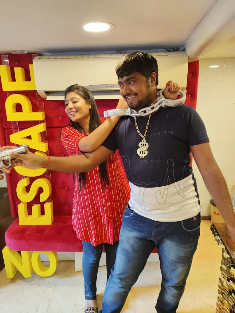 A young woman playfully puts a chain around a young man's neck, with "ESCAPE" and "NO" signs in the background.