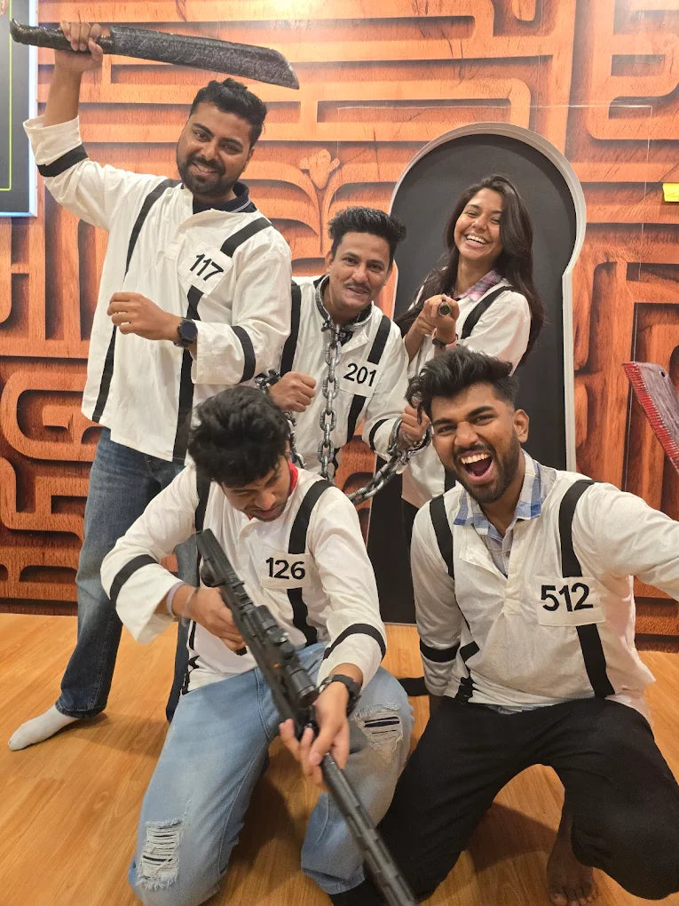 A group of young adults in matching outfits pose with props in a room with a maze-like backdrop.