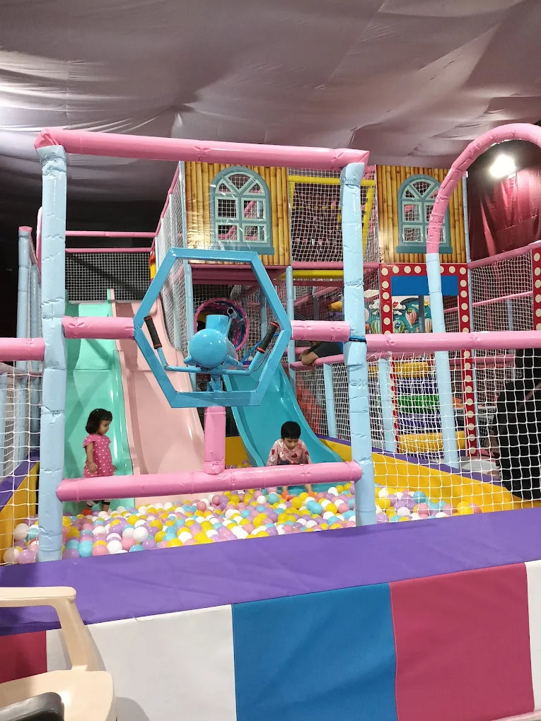 Children play in a colorful indoor playground with slides and a ball pit.