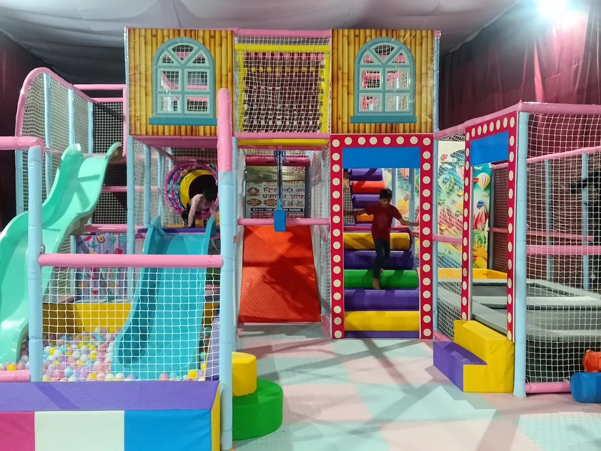 Children play in a colorful indoor playground with slides and ball pits.