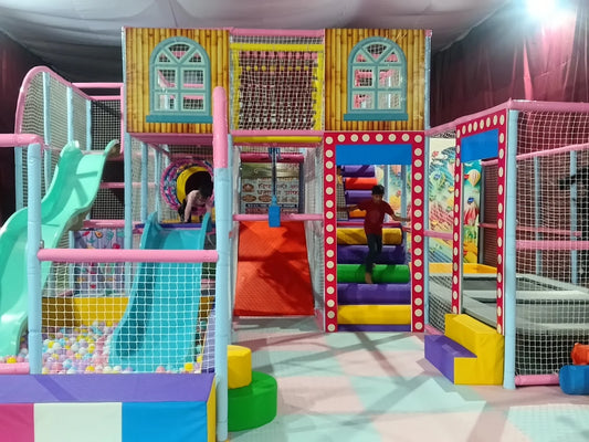 Children play in a colorful indoor playground with slides and ball pits.