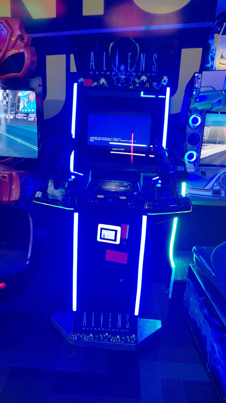 An "Aliens Extermination" arcade game with bright blue lights.