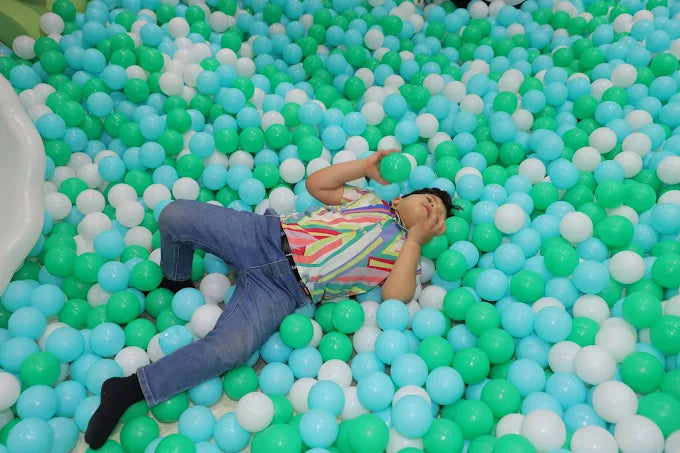 Child lying on a pit of multicolored balls in a playful setting