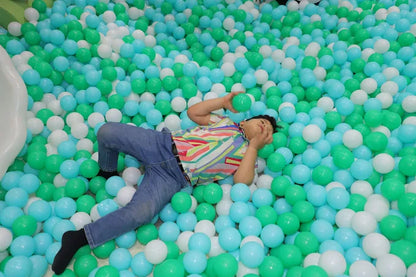 Child lying on a pit of multicolored balls in a playful setting