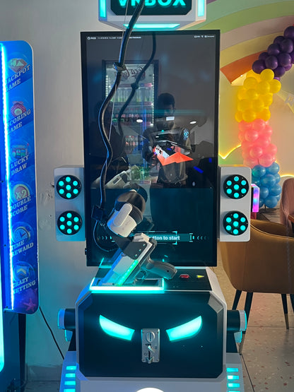 A person plays a VR shooting game at an arcade, with colorful balloons in the background.