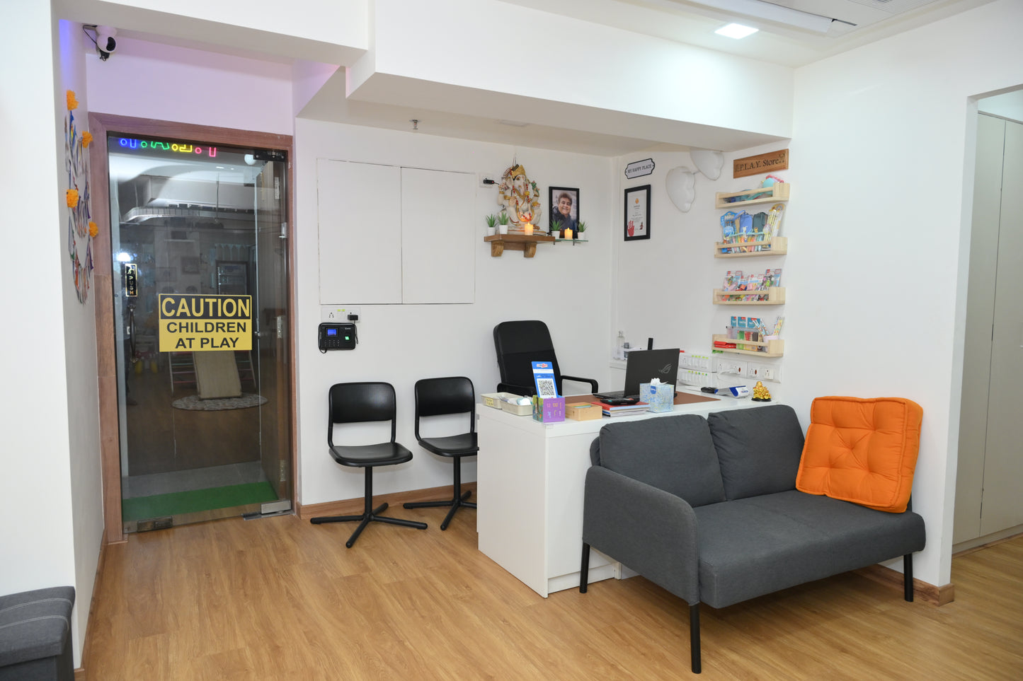 A reception area with a desk, chairs, and a sofa, likely for children.