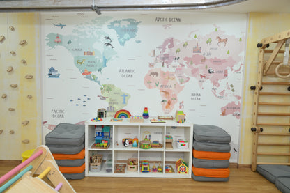 A colorful children's playroom with a world map mural, climbing wall, and toy shelves.