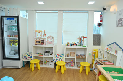 A brightly lit playroom with toys, a refrigerator, and children's furniture.