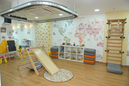 A brightly decorated playroom with a world map mural, climbing structures, and toys for young children.