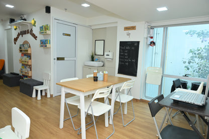 A bright, modern cafe with children's books and a menu board.