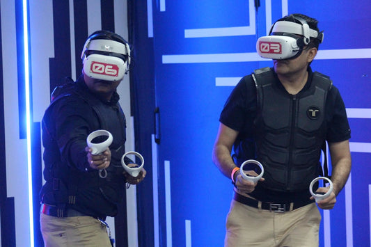Two men in VR headsets and vests play a virtual reality game, holding controllers.