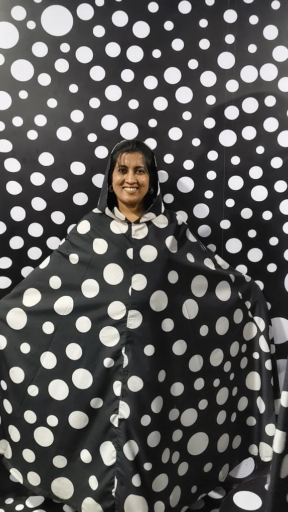 A woman smiles in a polka dot poncho in front of a polka dot backdrop.