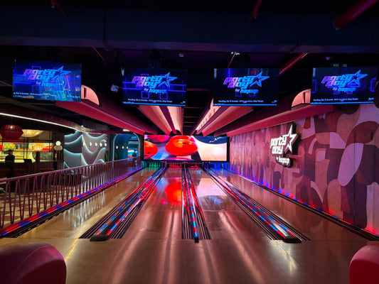 A bowling alley with neon lights and screens displaying the "Party Day by Hopup" logo.
