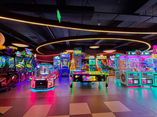 An arcade filled with colorful, neon-lit games and claw machines, with a checkered floor reflecting the vibrant lights.