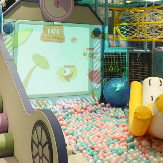 Children's indoor play area with ball pit, interactive screen, and colorful equipment.