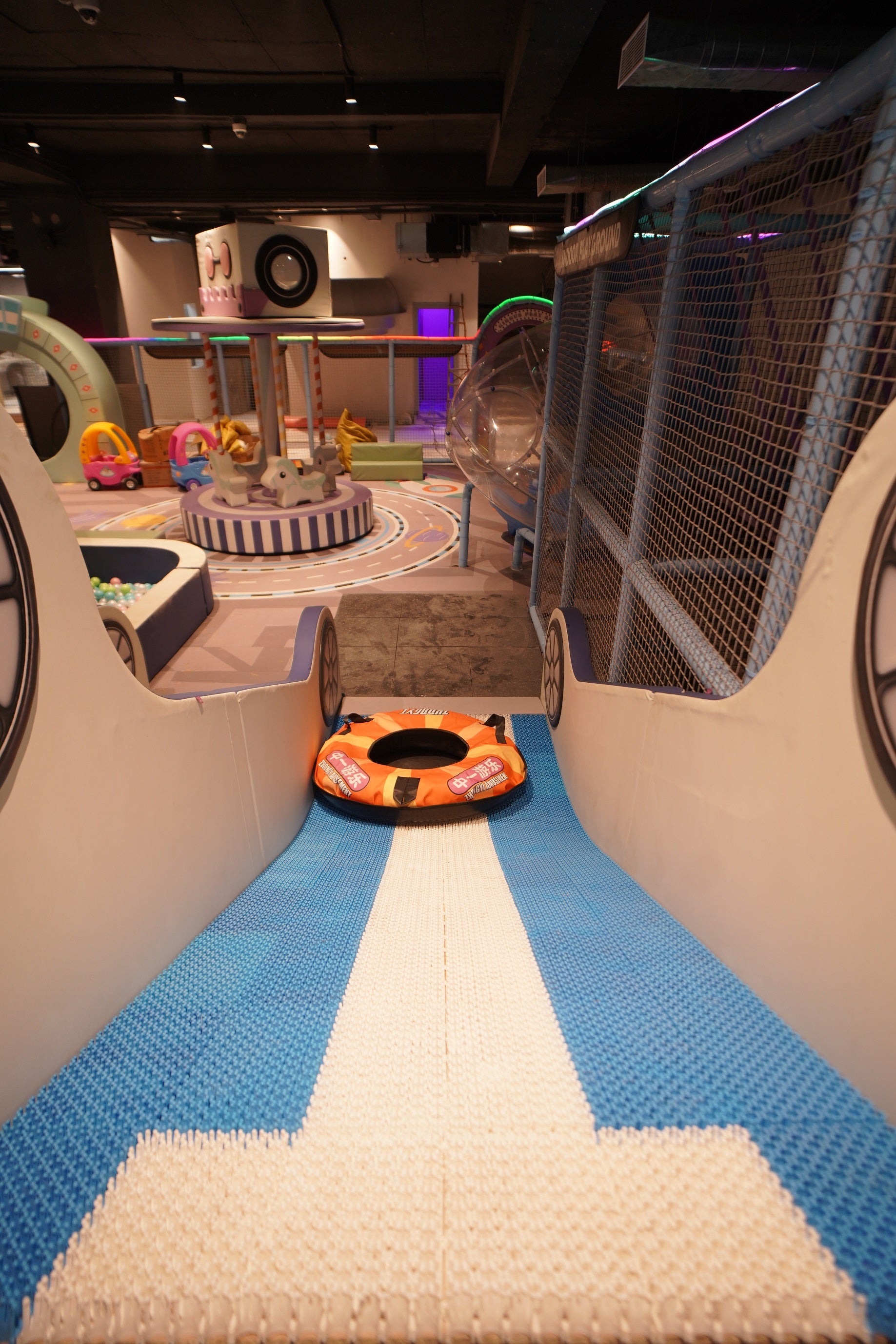 Children's play area with a blue and white striped floor, toy cars, and a small playground structure.