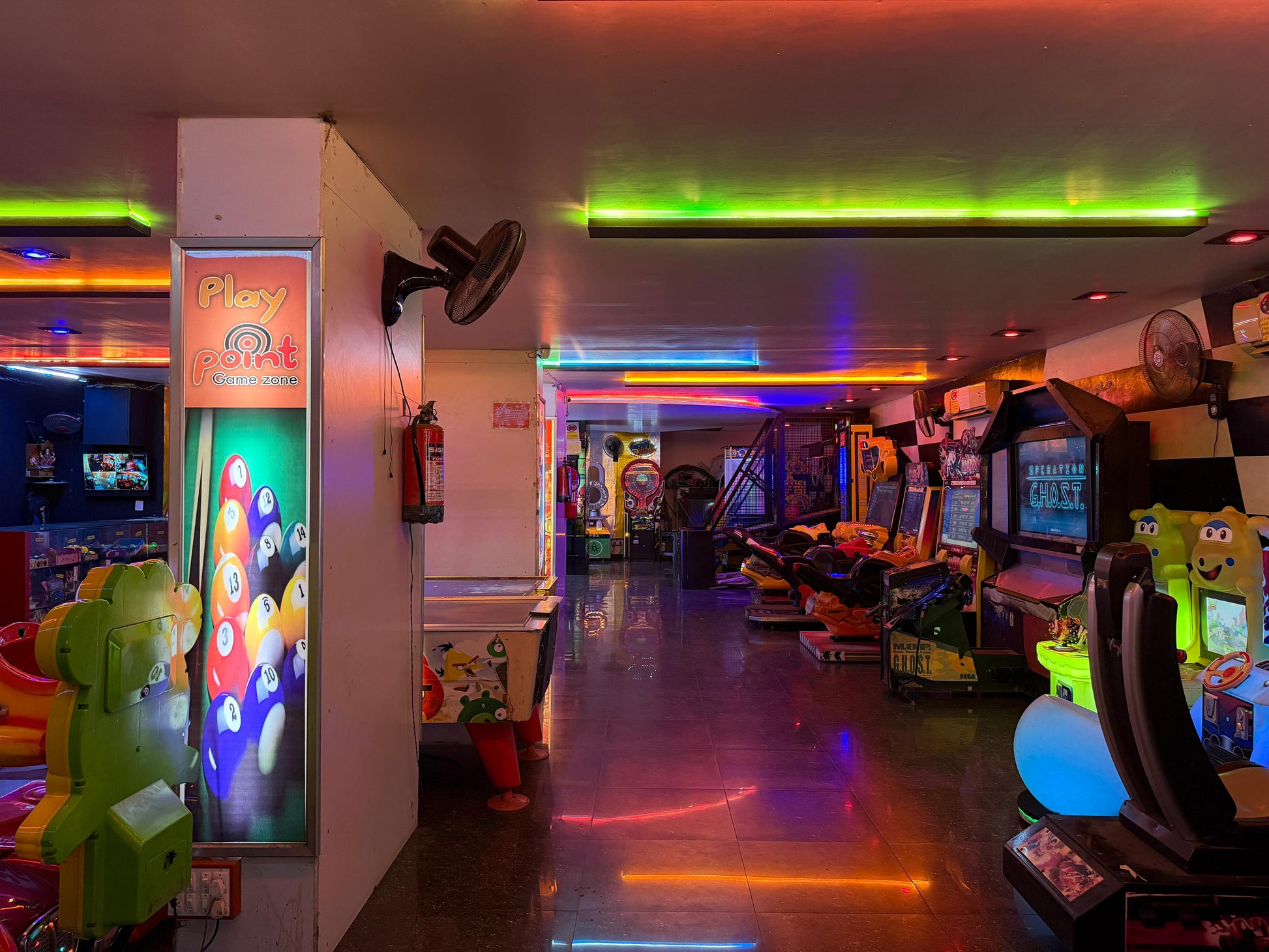 An arcade with colorful neon lights and various game machines.
