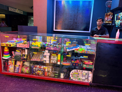 A man stands behind a counter filled with arcade prizes and toys at Coconut Cinema.