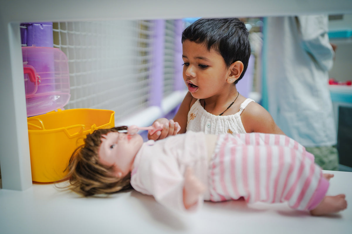 A young child plays with a doll in a brightly colored room.