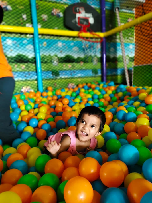 A young child plays in a ball pit filled with colorful balls.