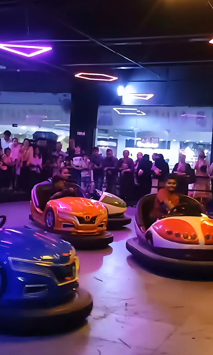 People enjoy riding bumper cars in a brightly lit indoor amusement park.