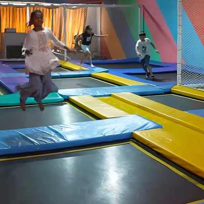 Children jumping on trampolines in an indoor play area.