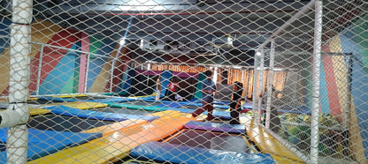 Children and adults jump on trampolines in a colorful indoor play area.