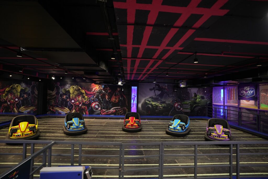 Bumper cars in an indoor arcade with superhero murals.