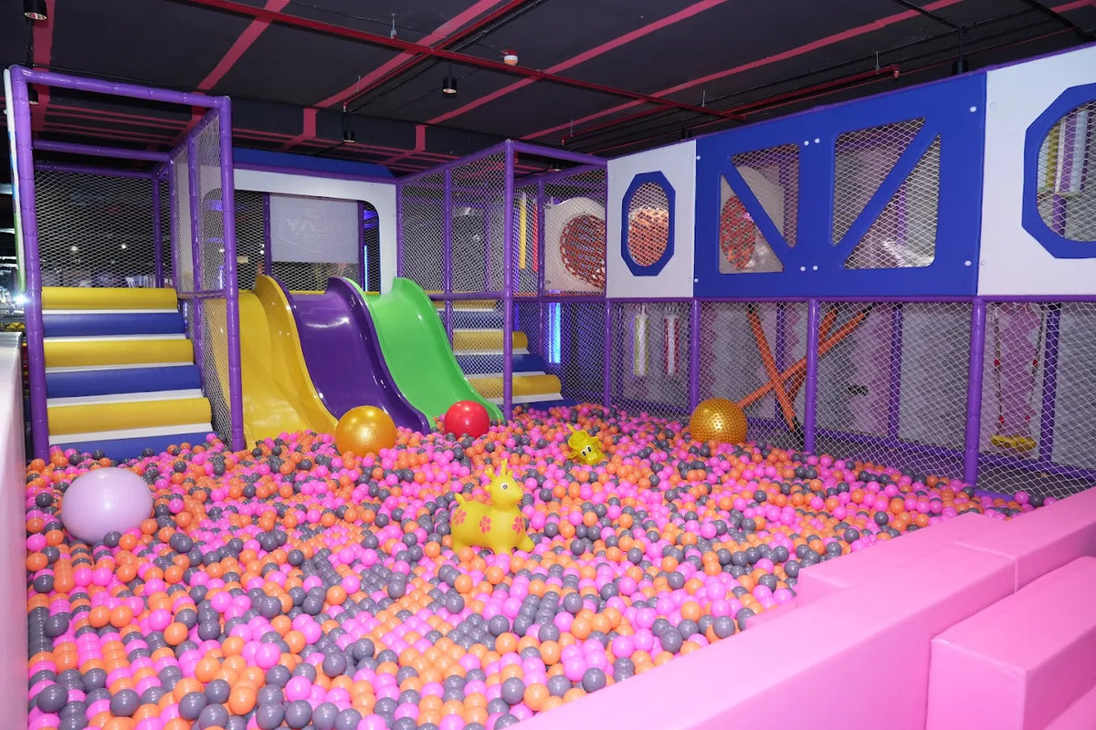 A colorful indoor playground with slides, a ball pit, and climbing structures for children.