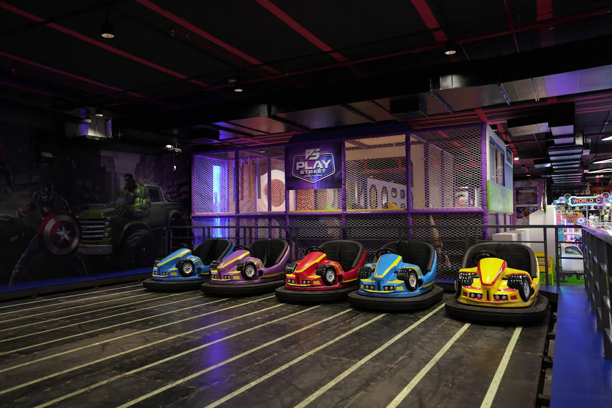 Bumper cars for children are lined up in an indoor play area with superhero murals.