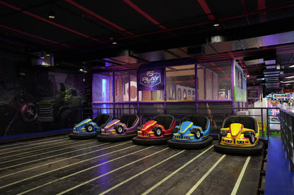 Bumper cars for children are lined up in an indoor play area with superhero murals.