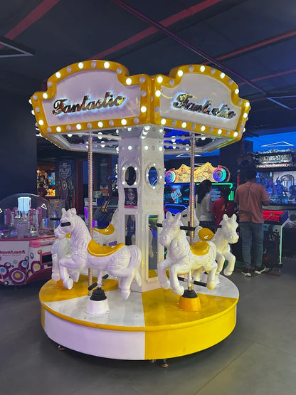 A carousel with white horses and yellow accents in an arcade.