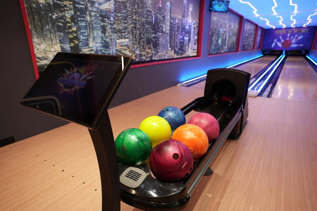 Bowling balls in a rack at a modern bowling alley with neon lights.