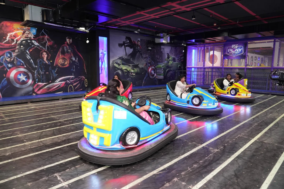 People enjoy riding bumper cars in an indoor amusement park with superhero-themed murals.