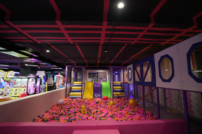 A colorful ball pit with slides and arcade games in an indoor play area for children.