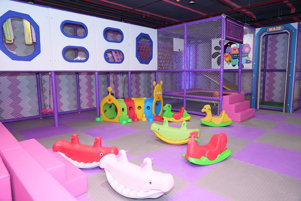 A colorful indoor playground with soft flooring and various animal-themed rocking toys for young children.
