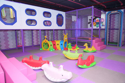A colorful indoor playground with soft flooring and various animal-themed rocking toys for young children.