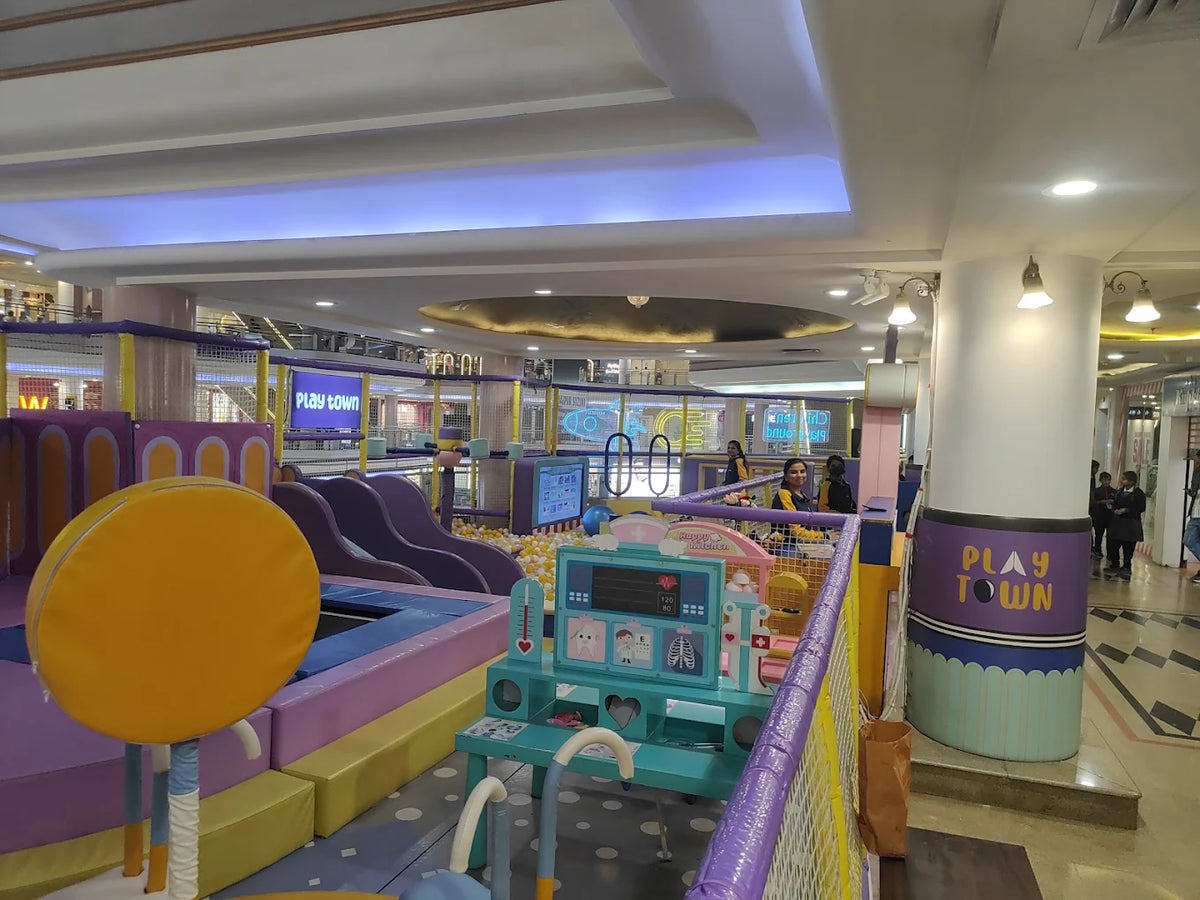 A colorful indoor playground with children playing, featuring slides, a ball pit, and a "Play Town" sign.