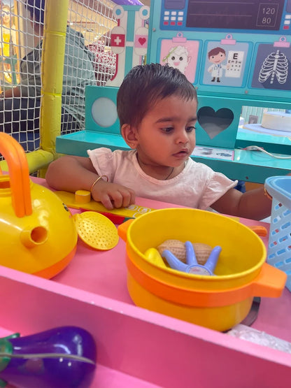 A young child plays with toys at a pretend doctor's office play station.