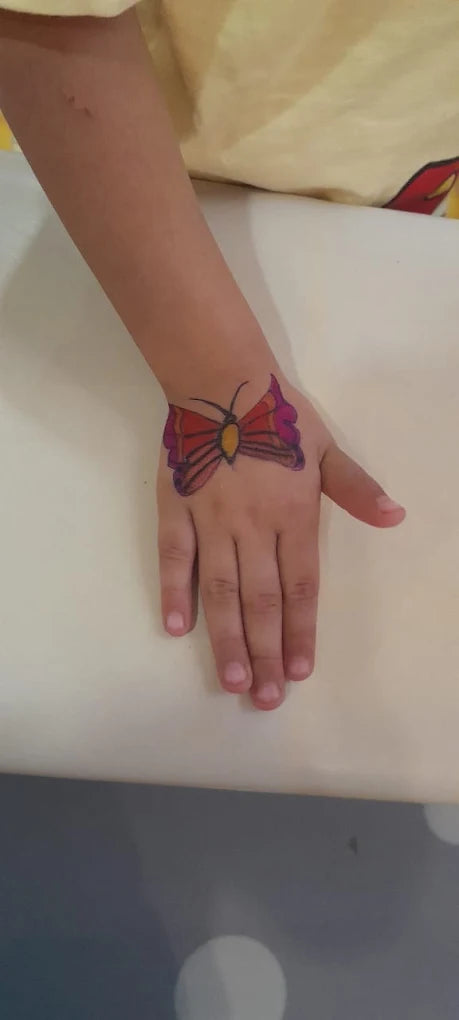A child's hand with a colorful butterfly drawing on it.