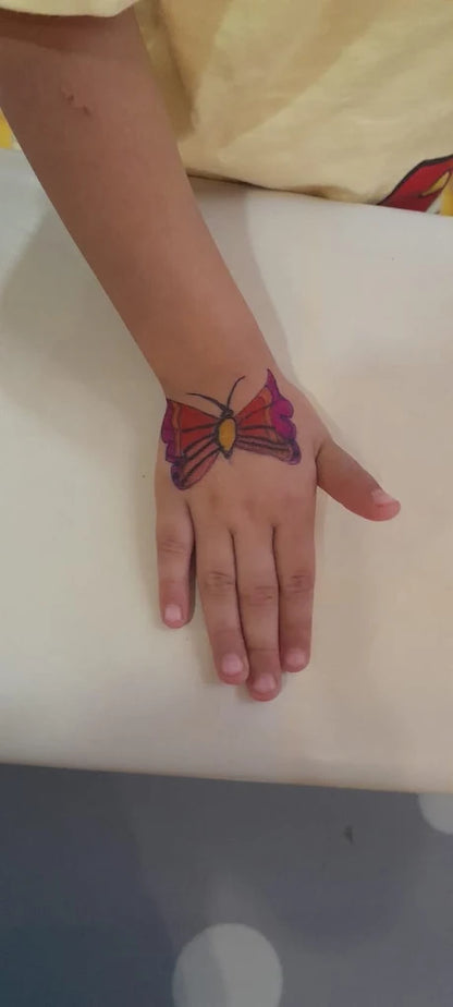 A child's hand with a colorful butterfly drawing on it.