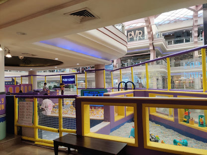 A colorful indoor playground with children playing in a ball pit and a soft play area.