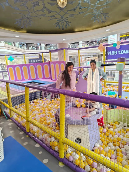 Children play in a colorful ball pit at an indoor playground.