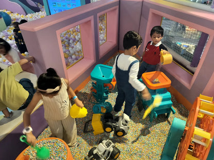 Children play in a ball pit with colorful toys and a ball dispenser.